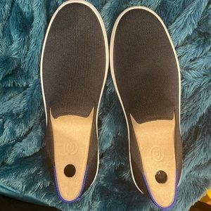 Rothy’s black sneakers with white and blue strip.